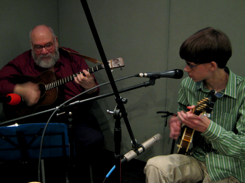 An adult and a teen playing mandolins in a radio studio