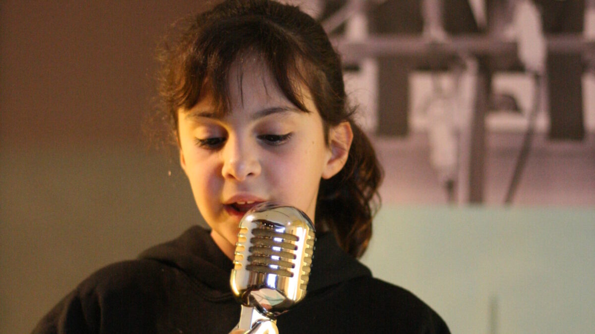 A youth standing behind a podium speaking into a microphone in front of banners of Martin Luther King, Jr.