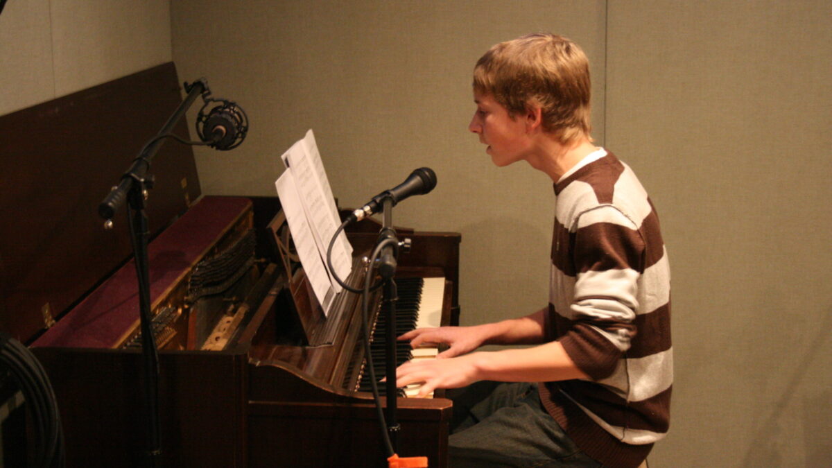 A youth playing a piano in a radio studio