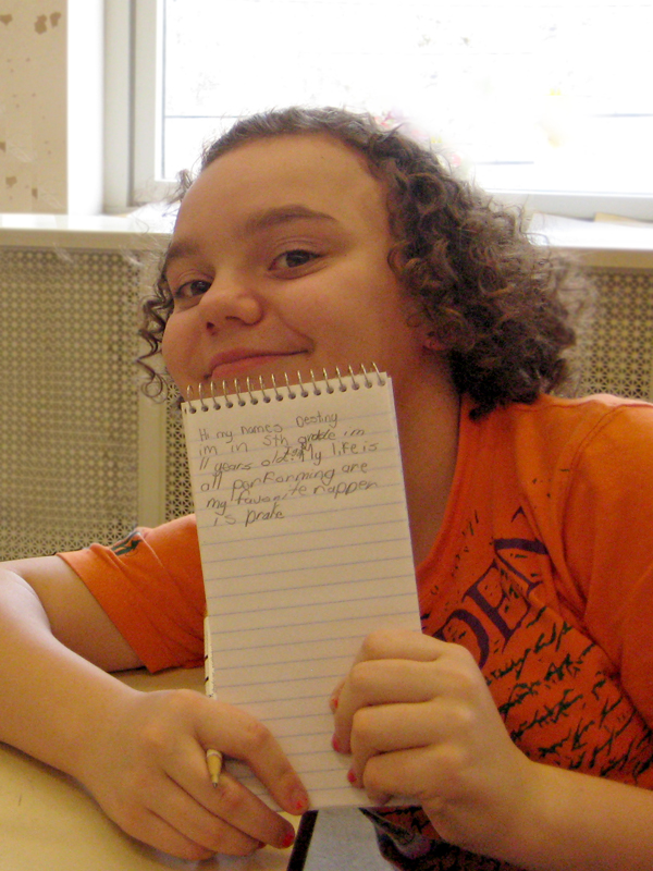 A youth holding a notepad and smiling at the microphone