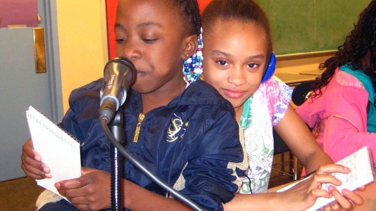 Sunnyside Two youth holding pieces of paper standing behind a microphone