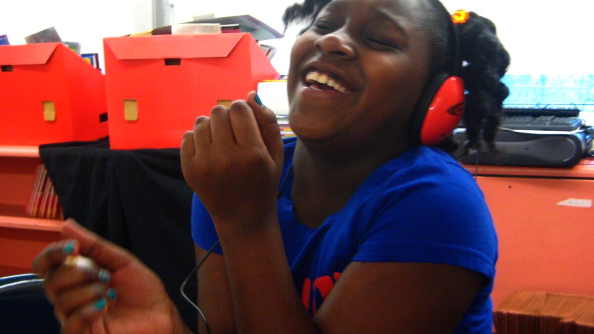 Sunnyside A youth wearing headphones smiling and laughing.