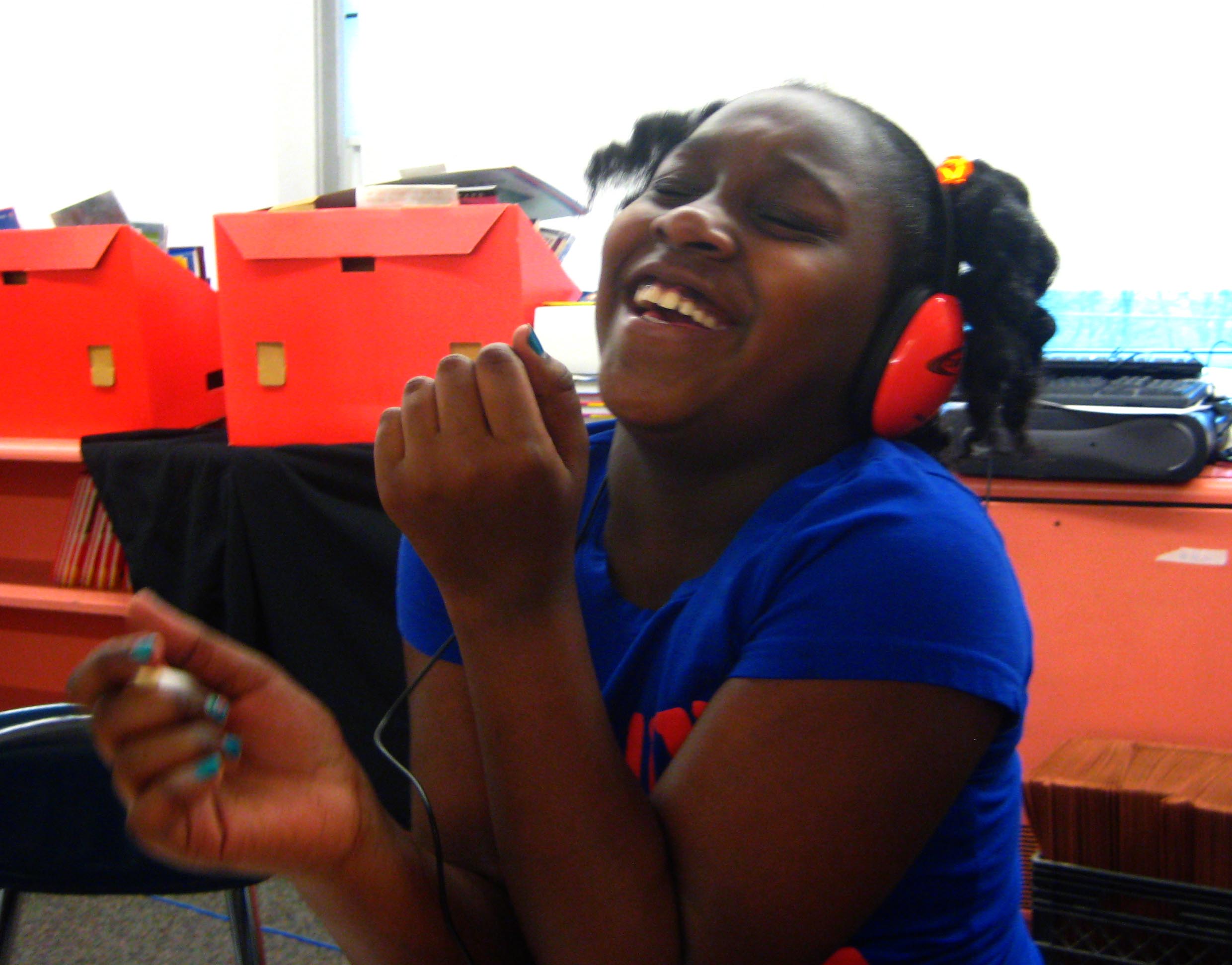A youth wearing headphones smiling and laughing.