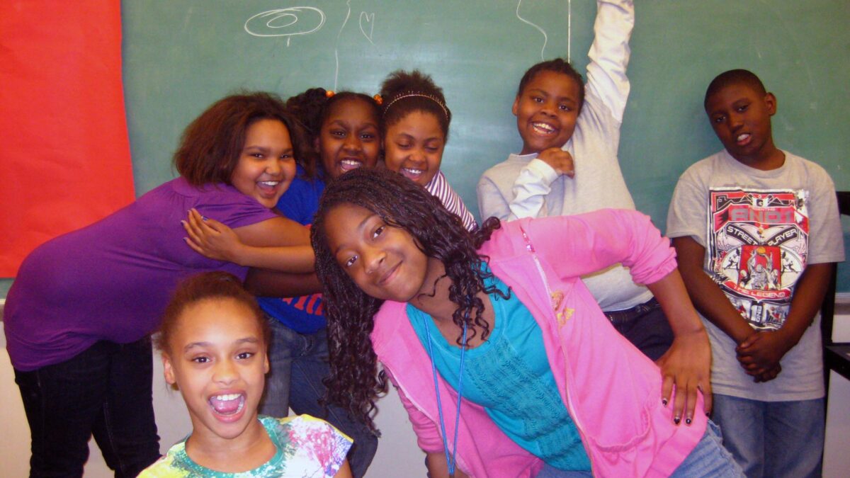 Sunnyside Seven youth smiling and posing in front of a chalkboard
