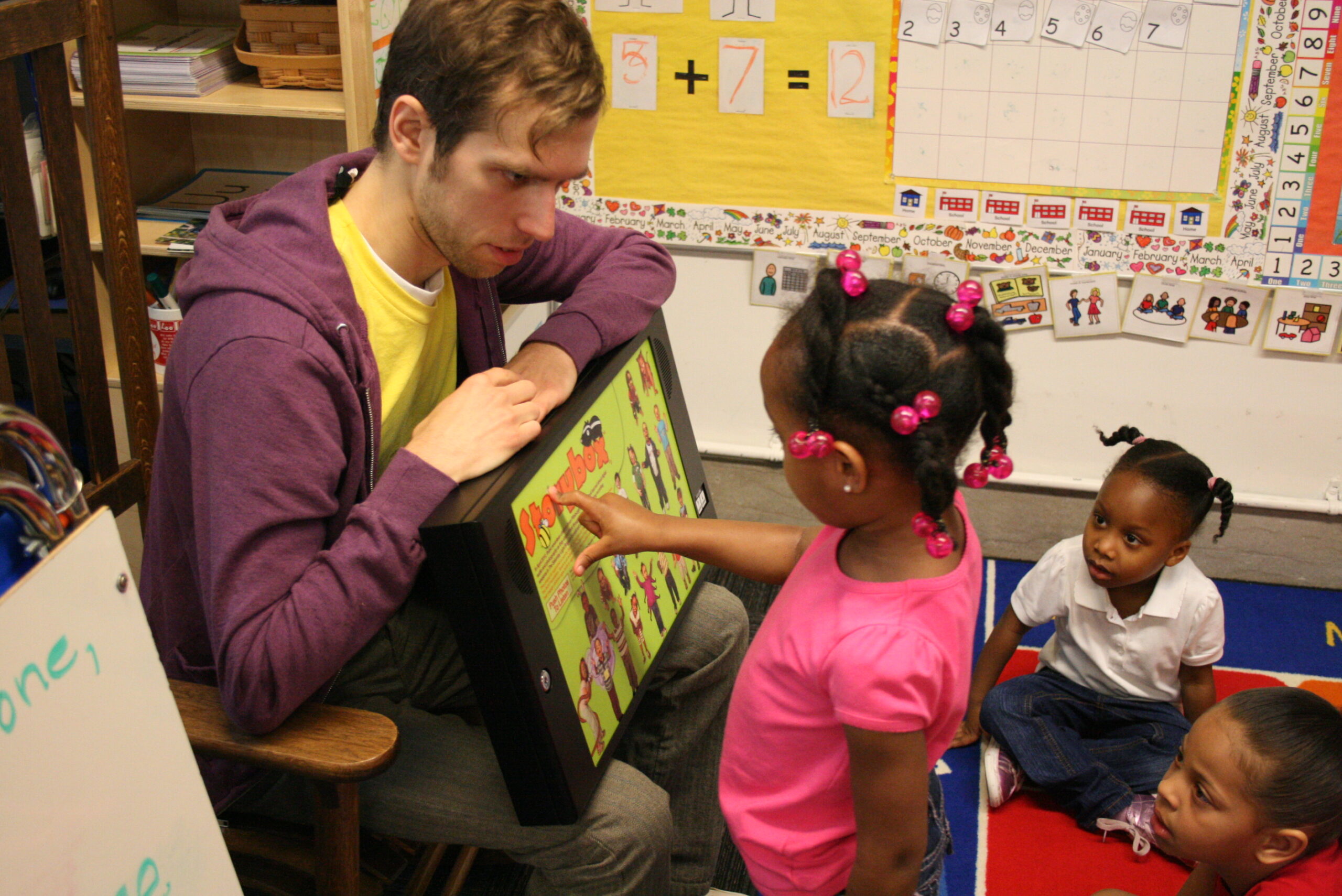 An adult and a youth interacting with a tablet in a classroom