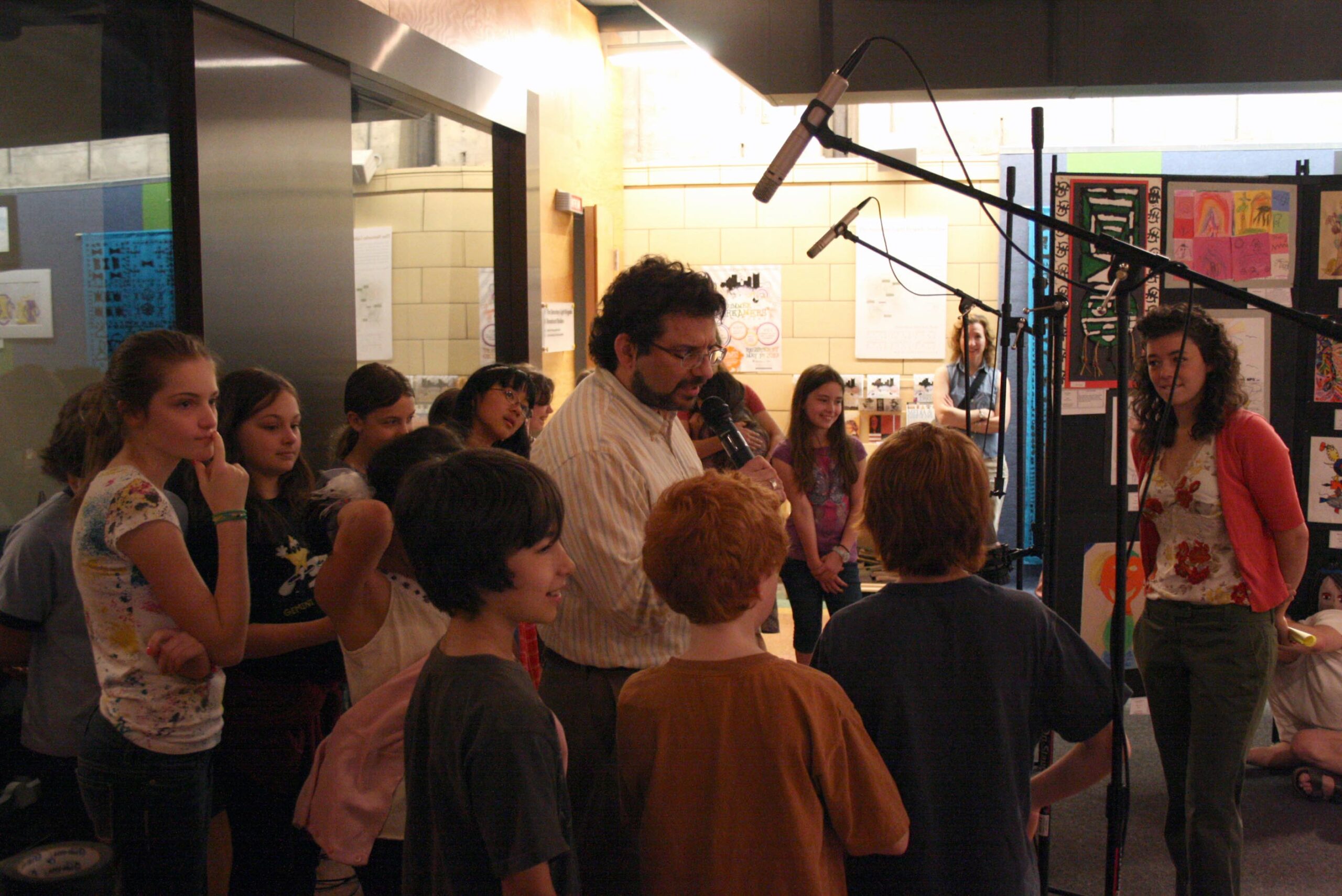 An adult interviewed a choir of youth standing behind microphones