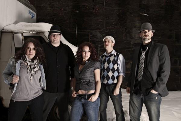 Five adults posing in front of a black wall