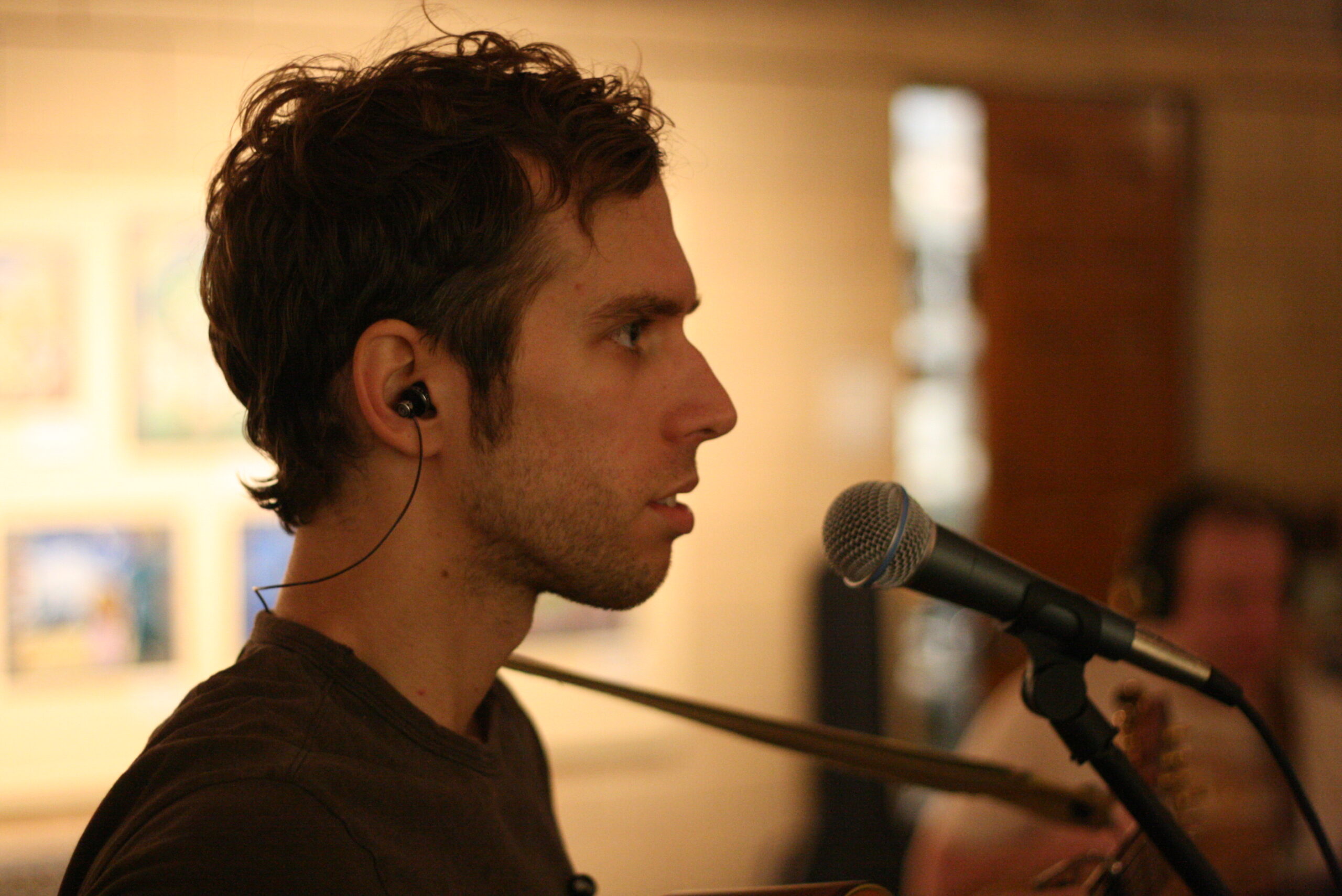 An adult wearing earbuds standing behind a microphone