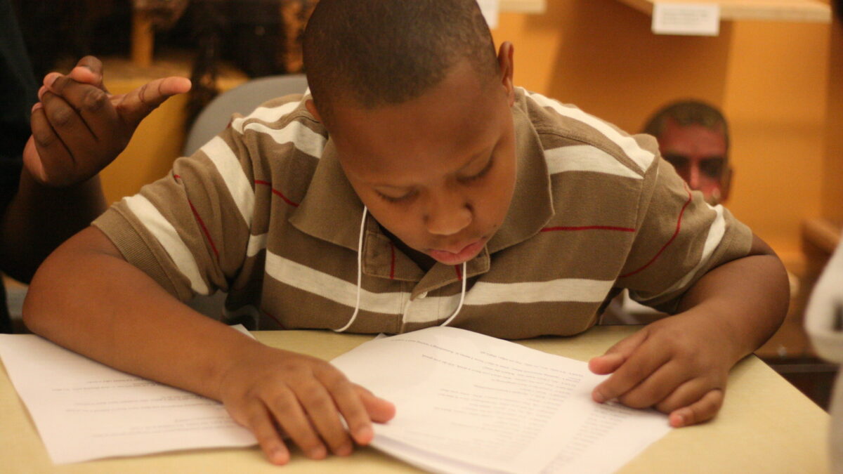 A youth looking at a piece of paper in a classroom