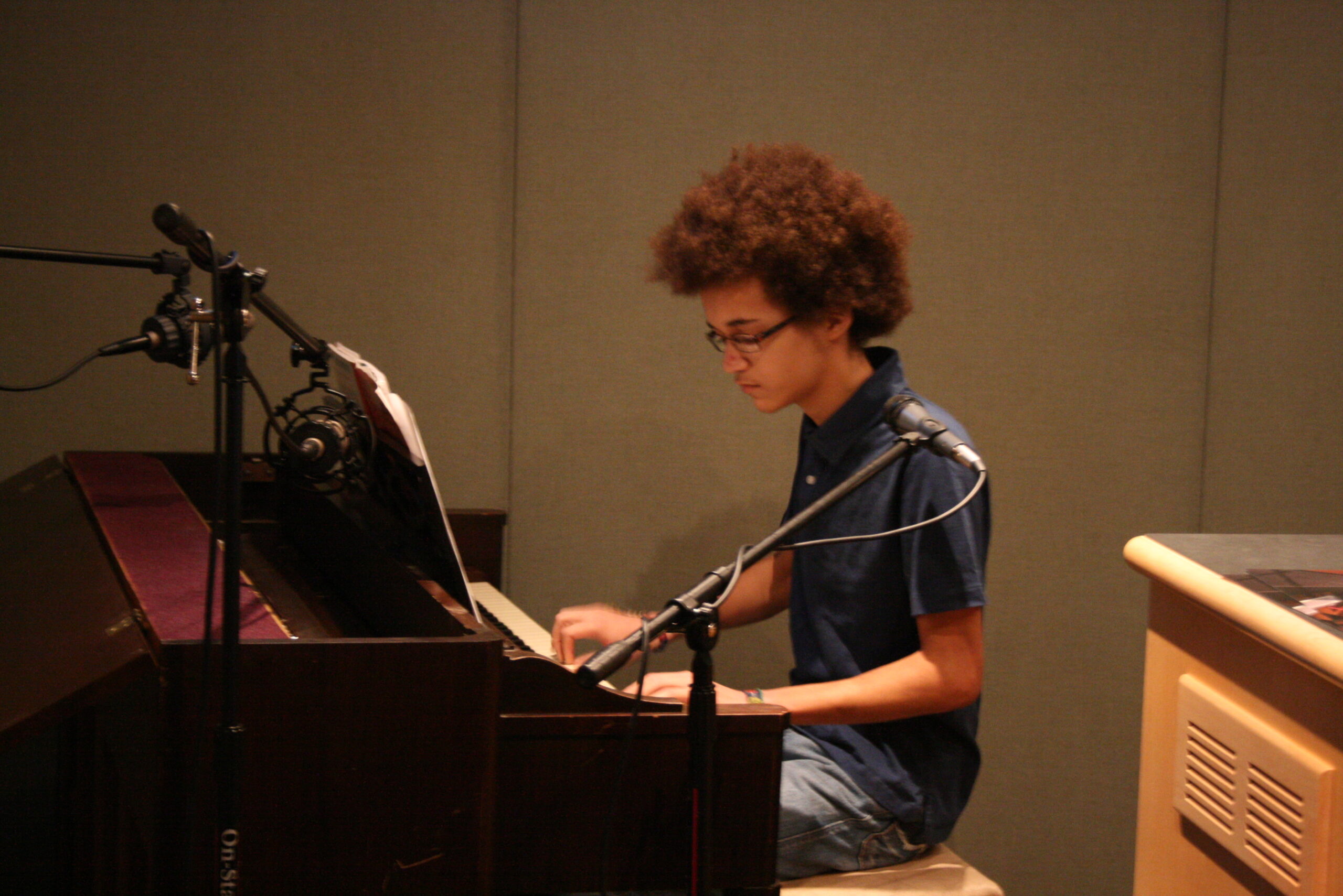A teen playing a piano in a radio studio