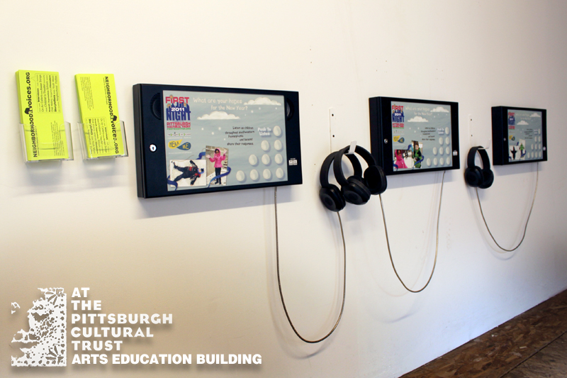 Three boxes on a wall connected to headphones next to yellow flyers