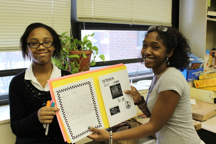 Two youth holding a yellow posterboard in a classroom