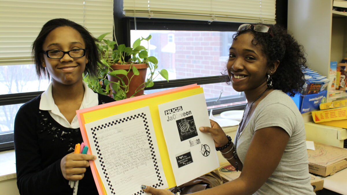 Two youth holding a yellow posterboard in a classroom