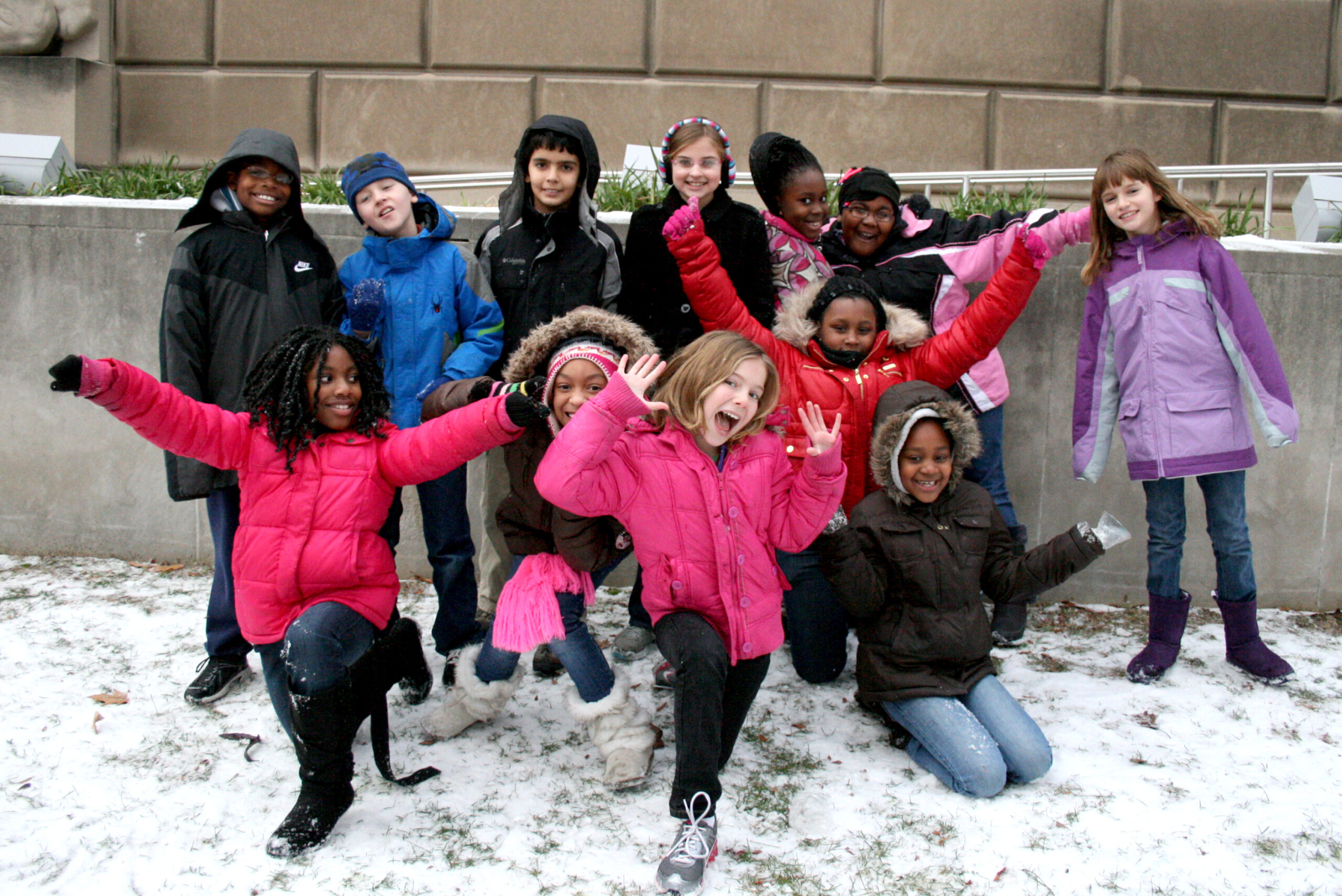 Twelve youth smiling and posing in front of a wall
