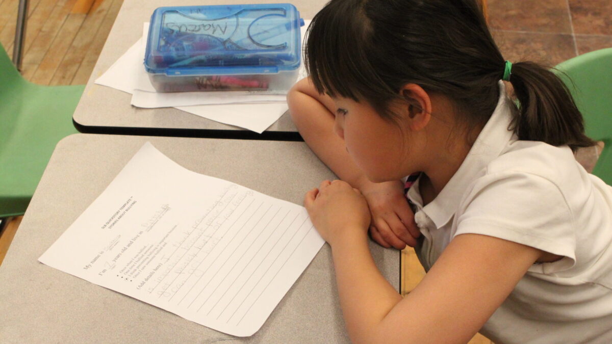 A youth looking at a piece of paper in a classroom