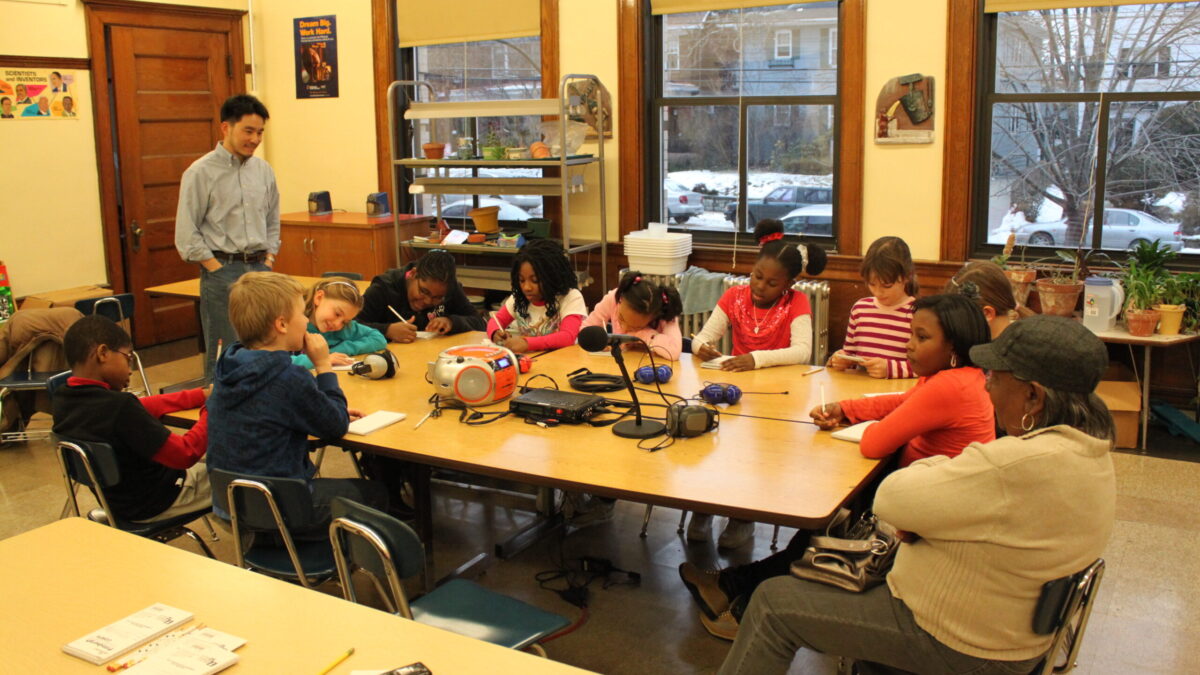 Ten youth and two adults around a table in a classroom