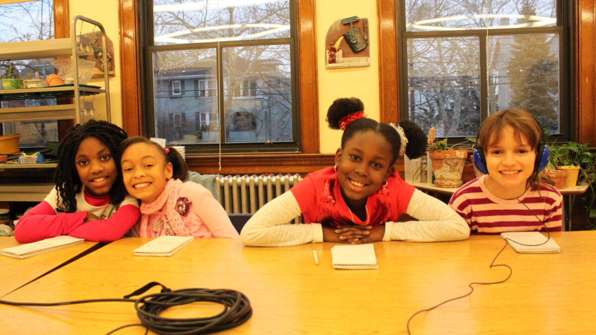 Four youth smiling while sitting at a classroom table