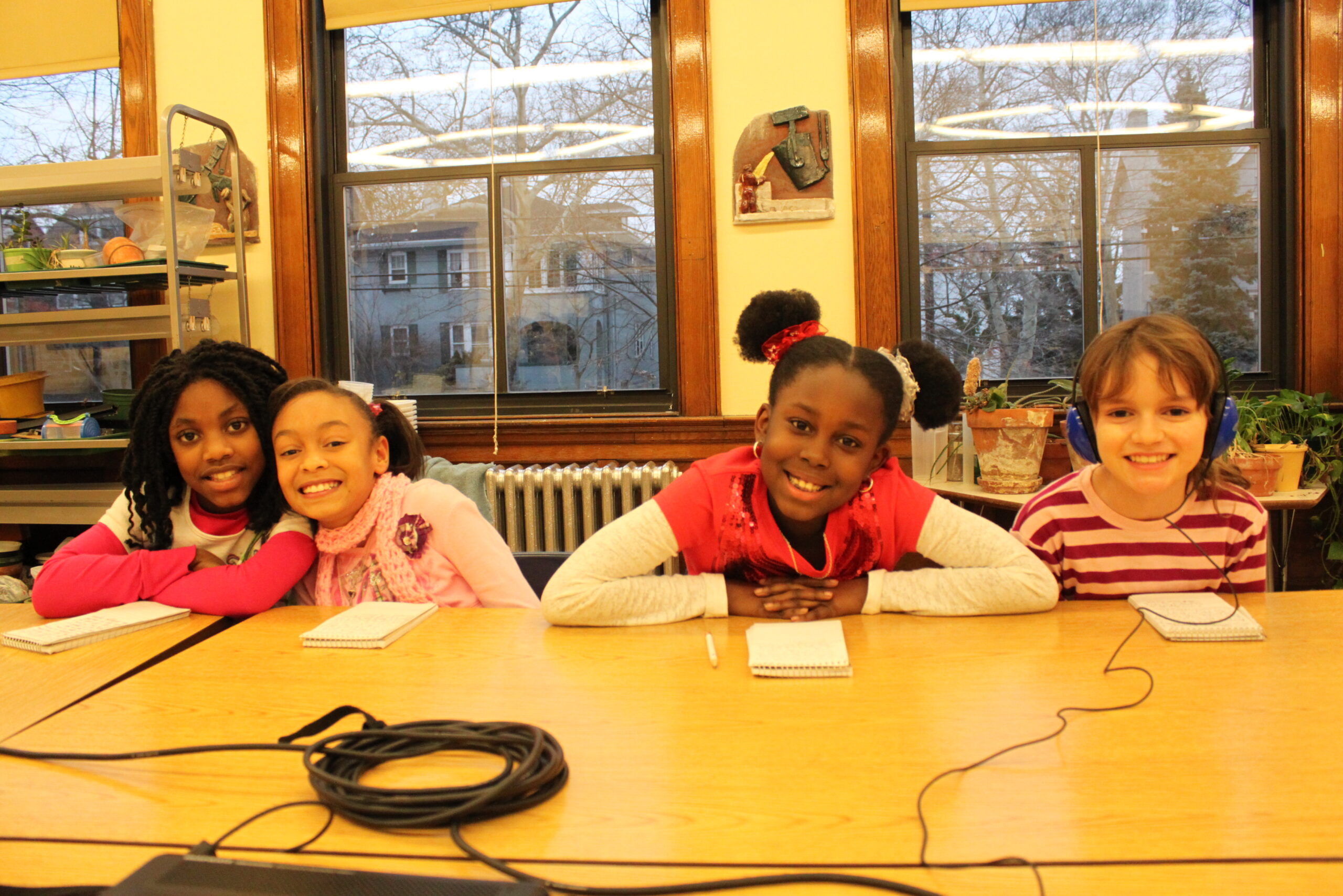Four youth smiling while sitting at a classroom table