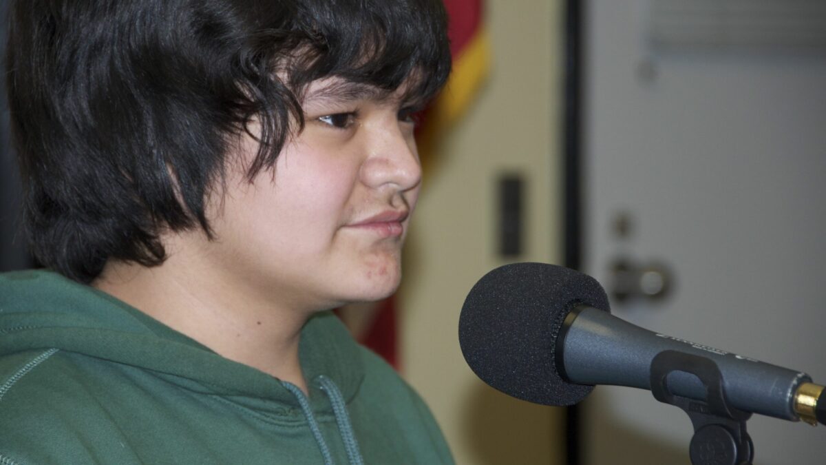A teen sitting behind a microphone