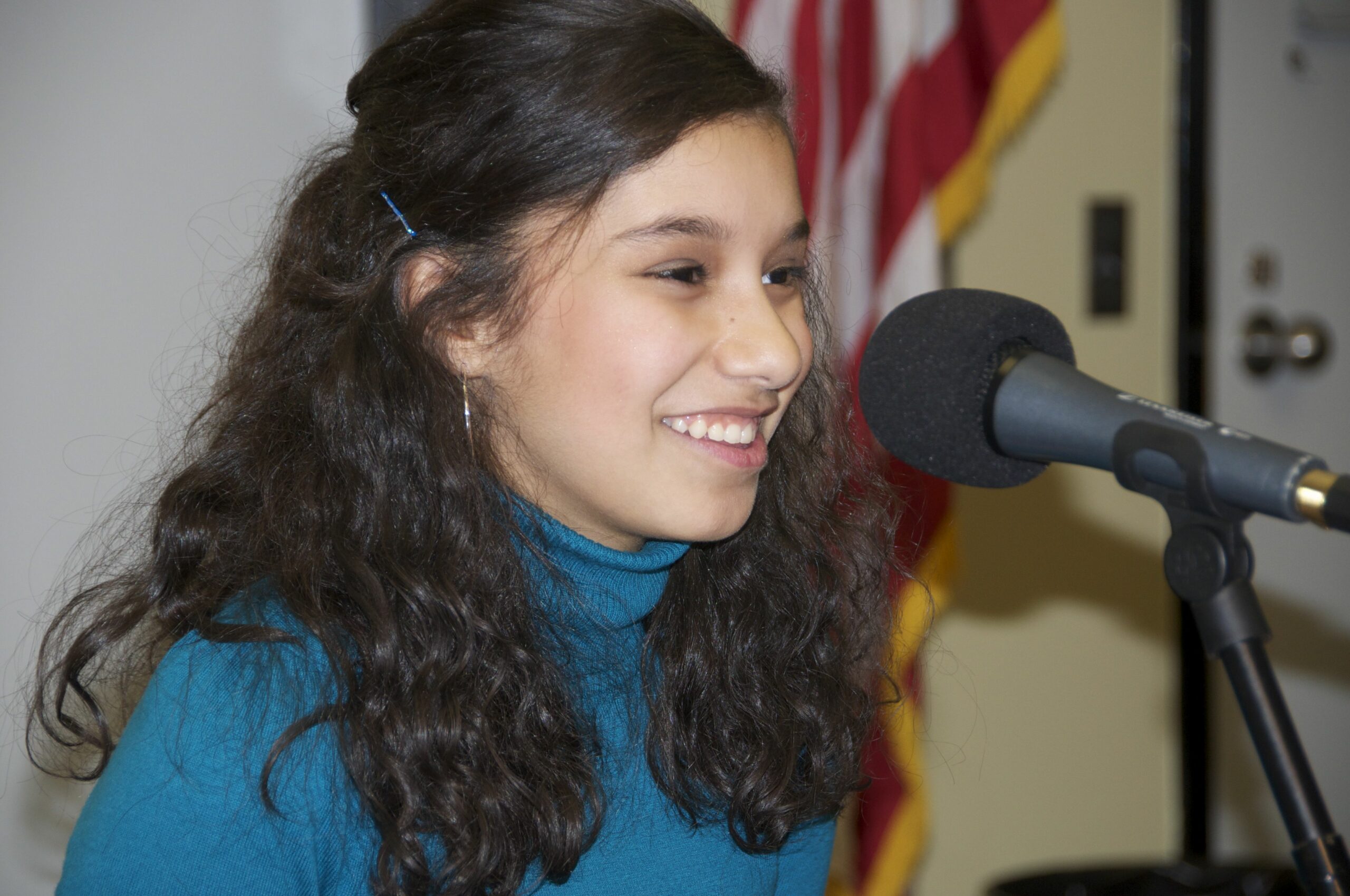 A teen smiling and sitting behind a microphone