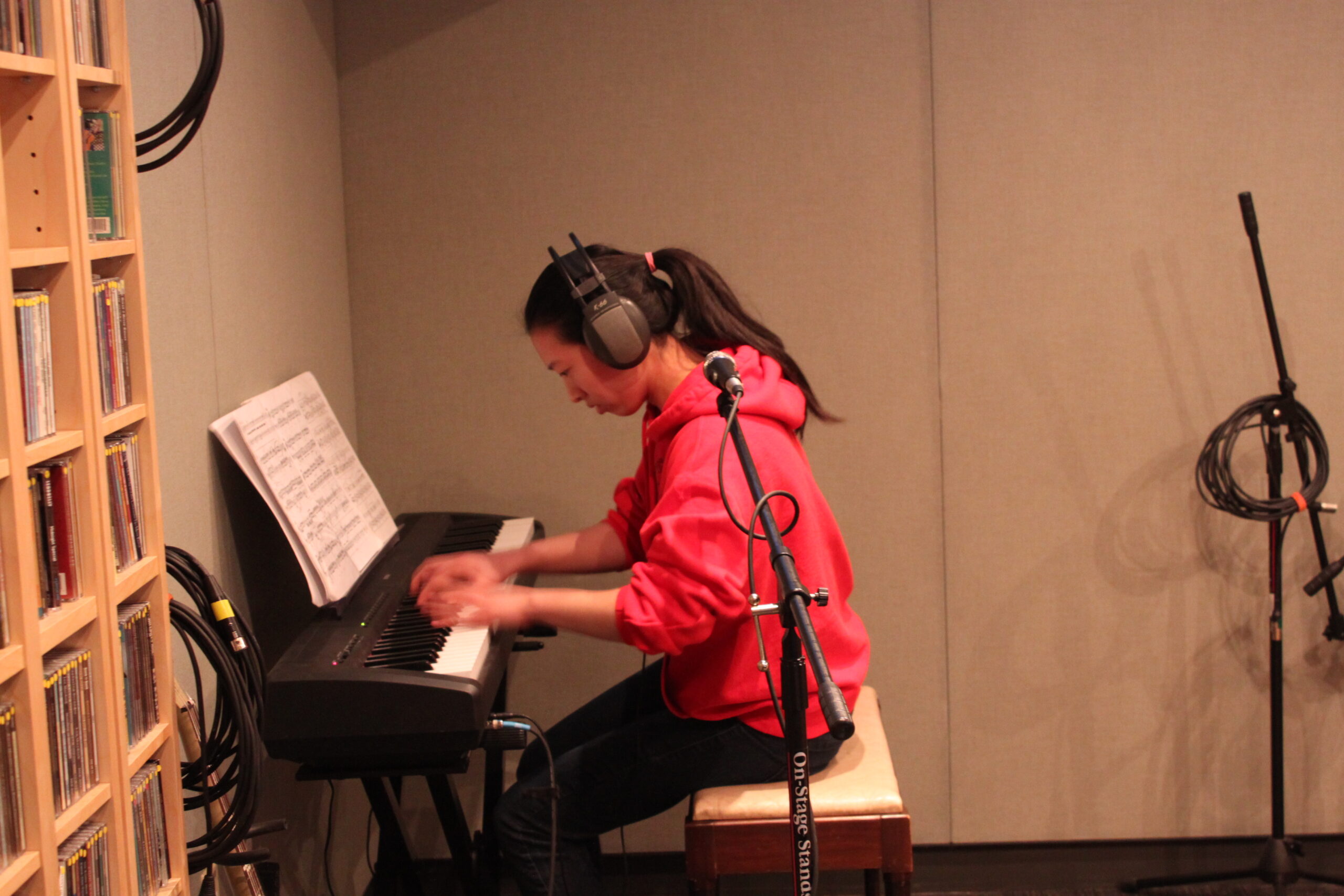 A teen playing a piano keyboard in a radio studio
