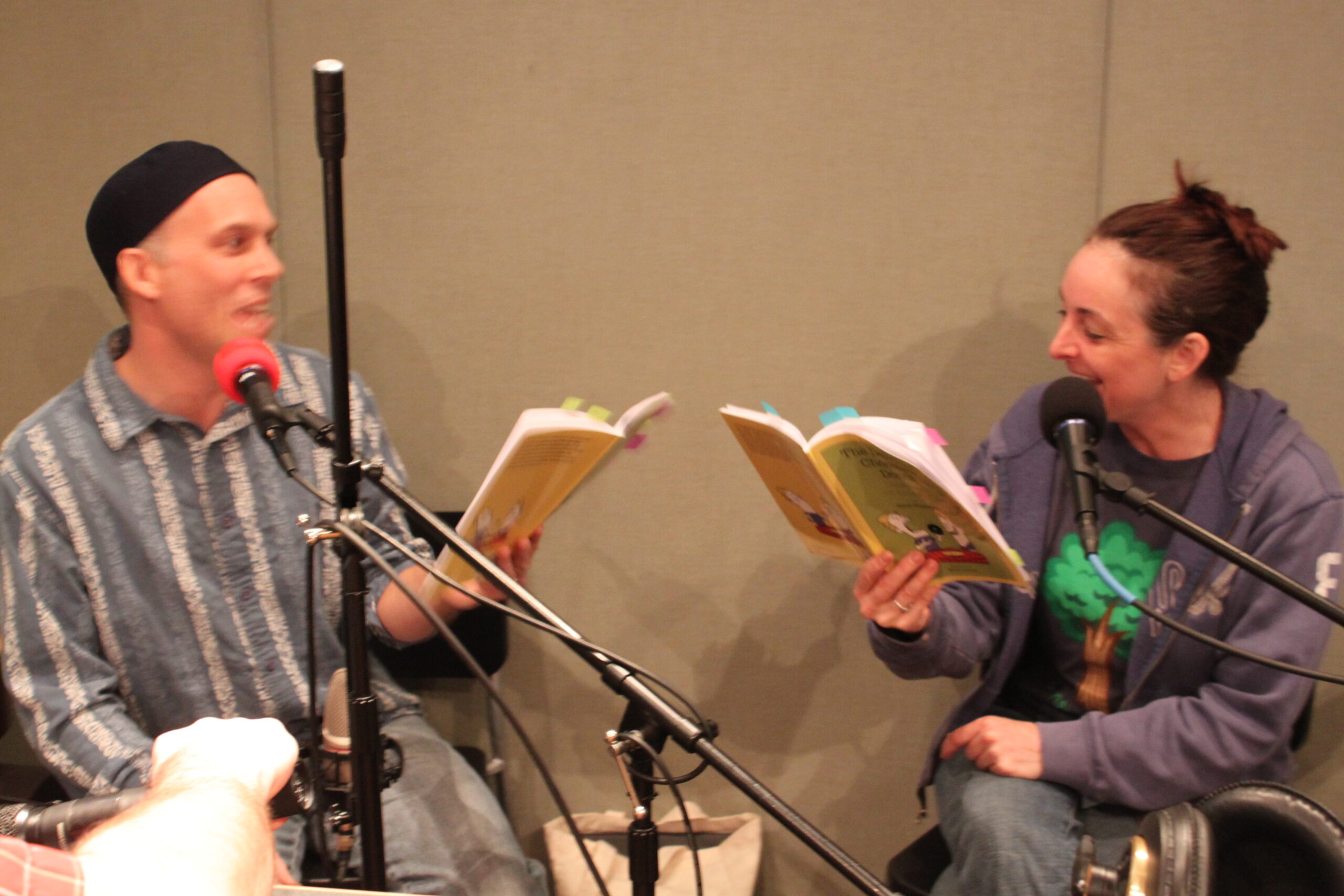 Two adults reading books in a radio studio