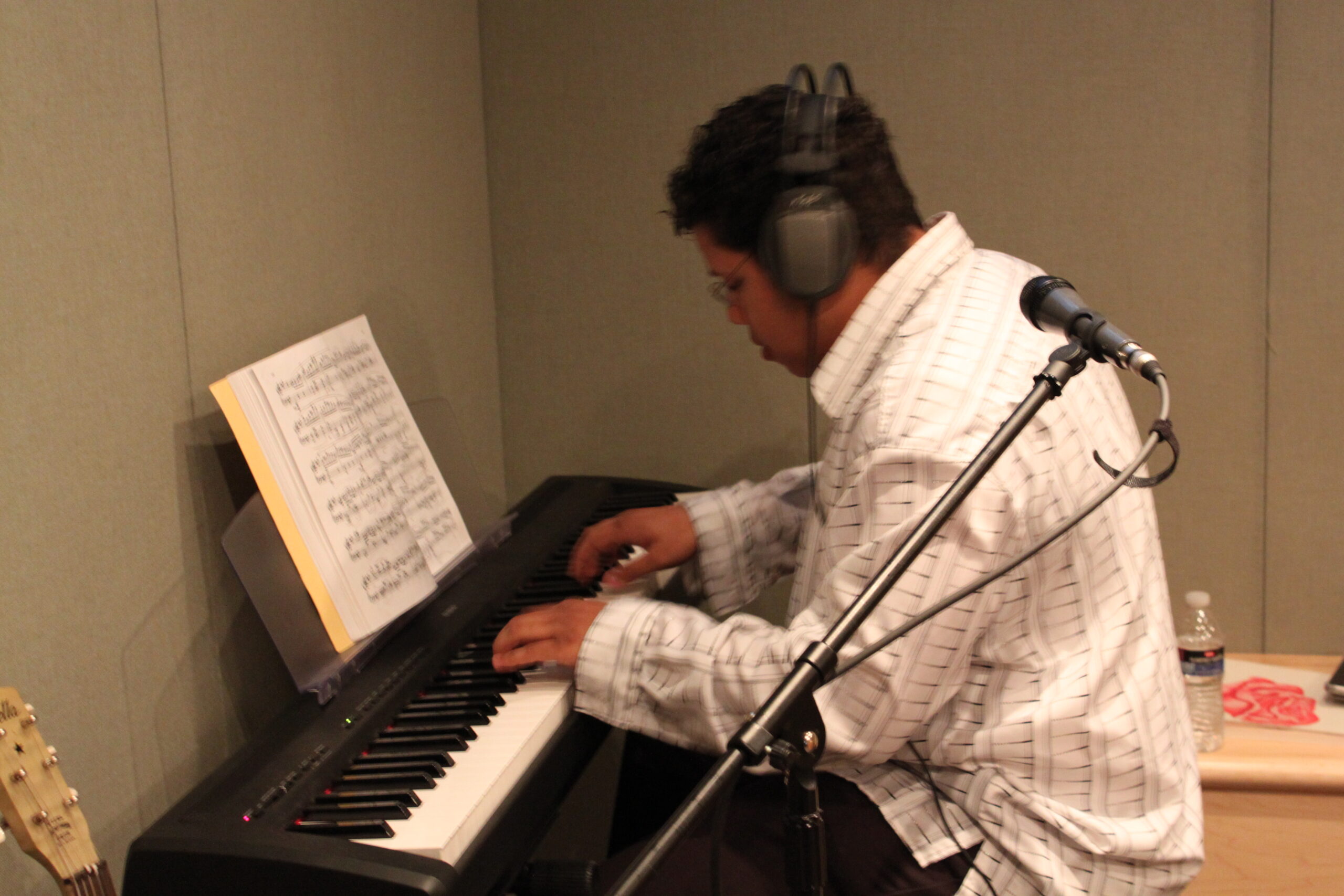A teen playing a piano keyboard in a radio studio