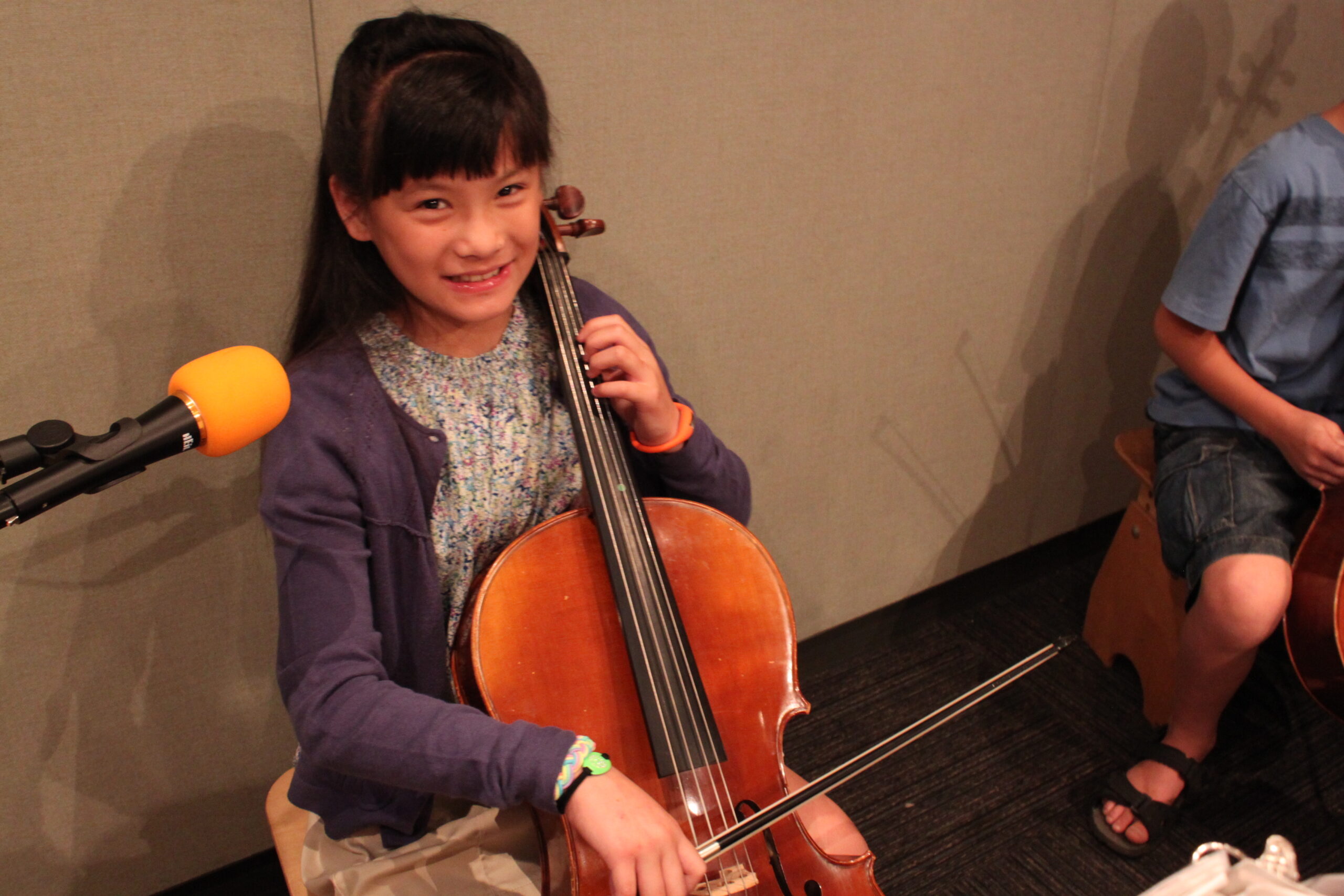 A youth playing a cello in a radio studio
