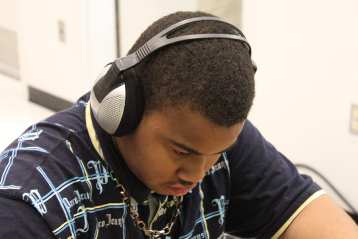 A teen wearing headphones looking down