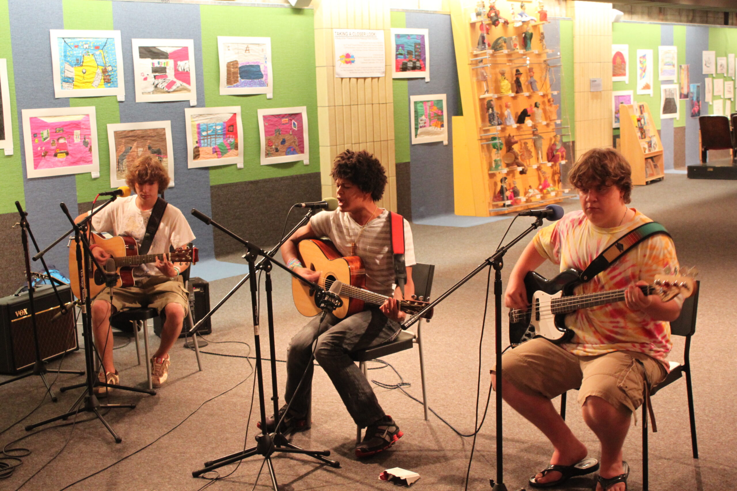 Two teens playing acoustic guitar and one teen playing electric bass