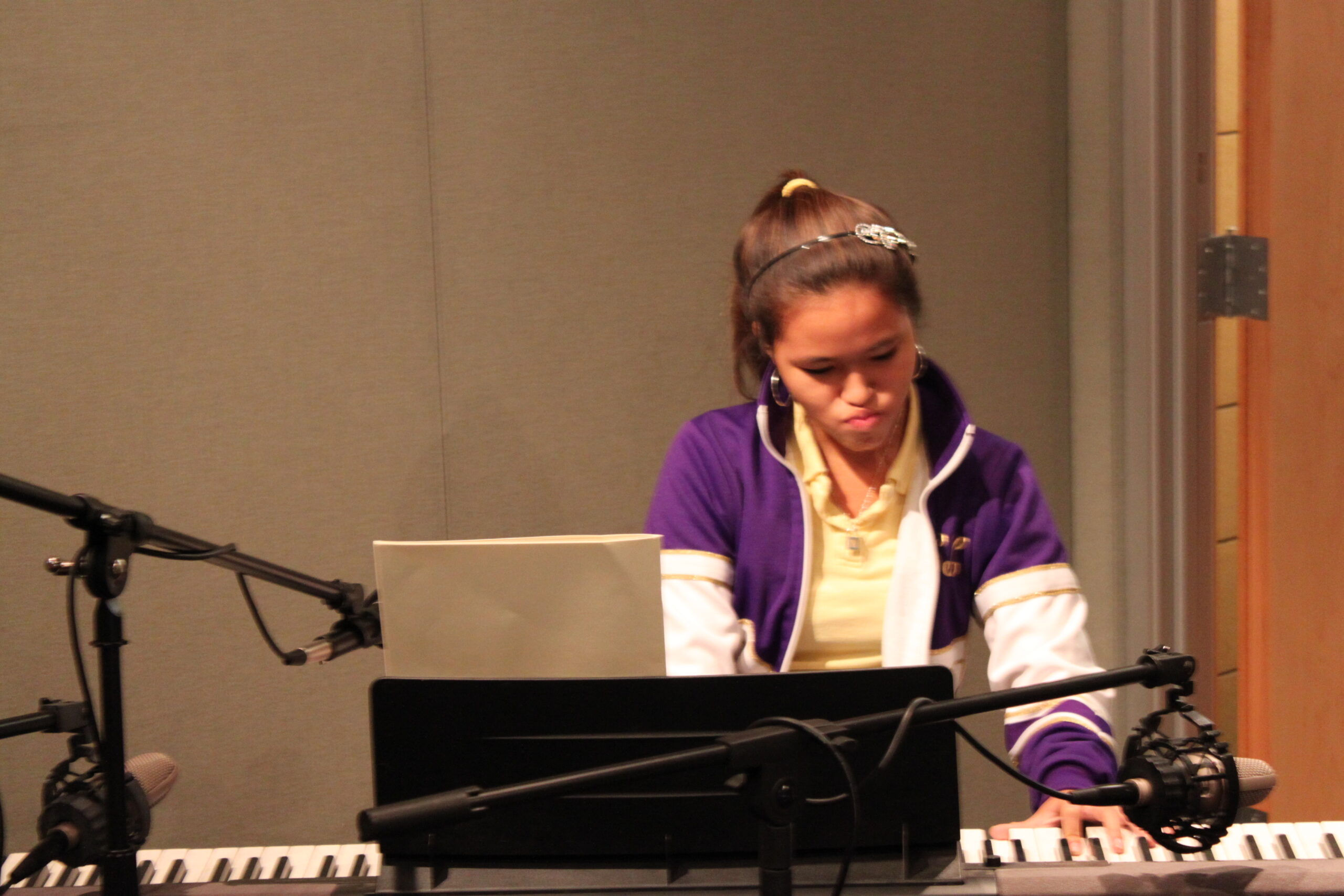 A youth playing a piano keyboard in a radio studio