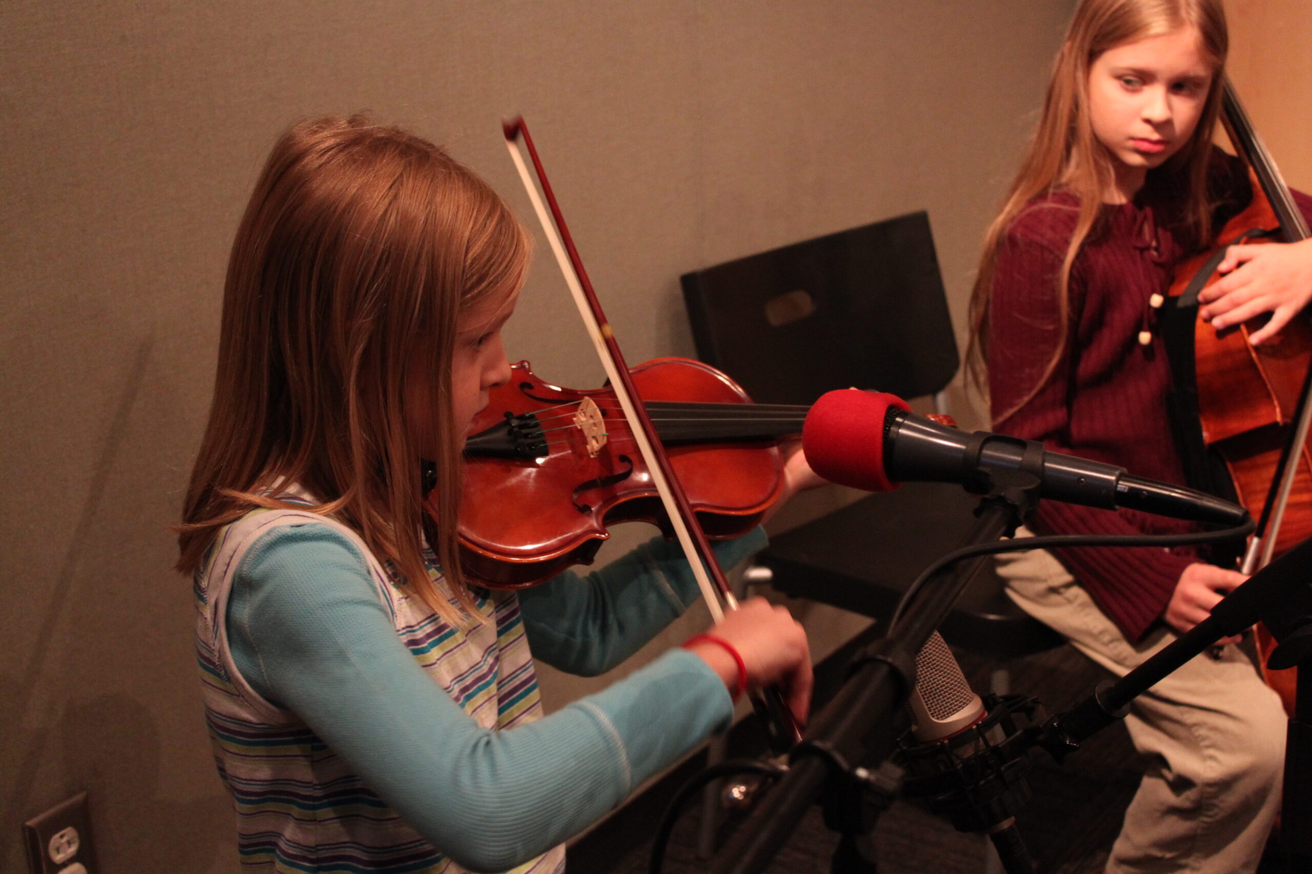 A youth playing a violin and a youth playing a cello in a radio studio