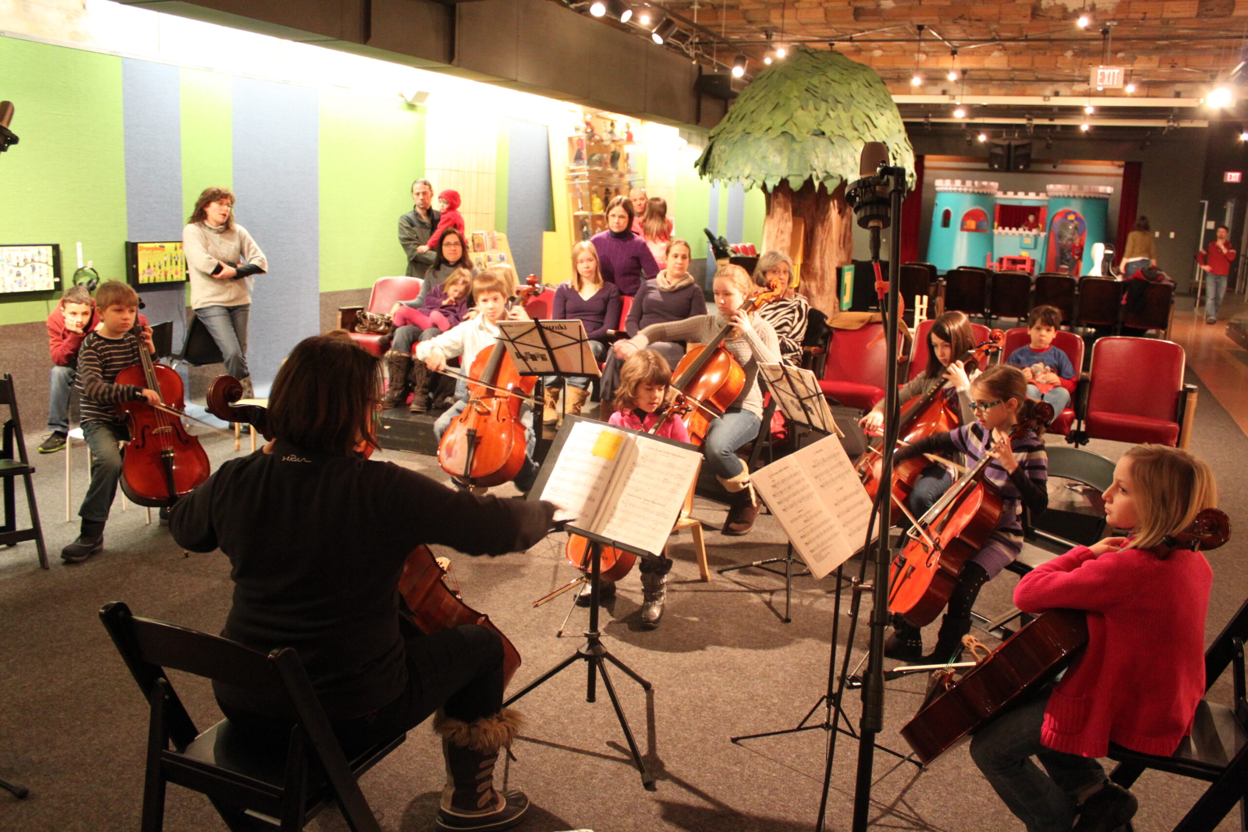 A group of youth playing cellos looking at sheet music on music stands