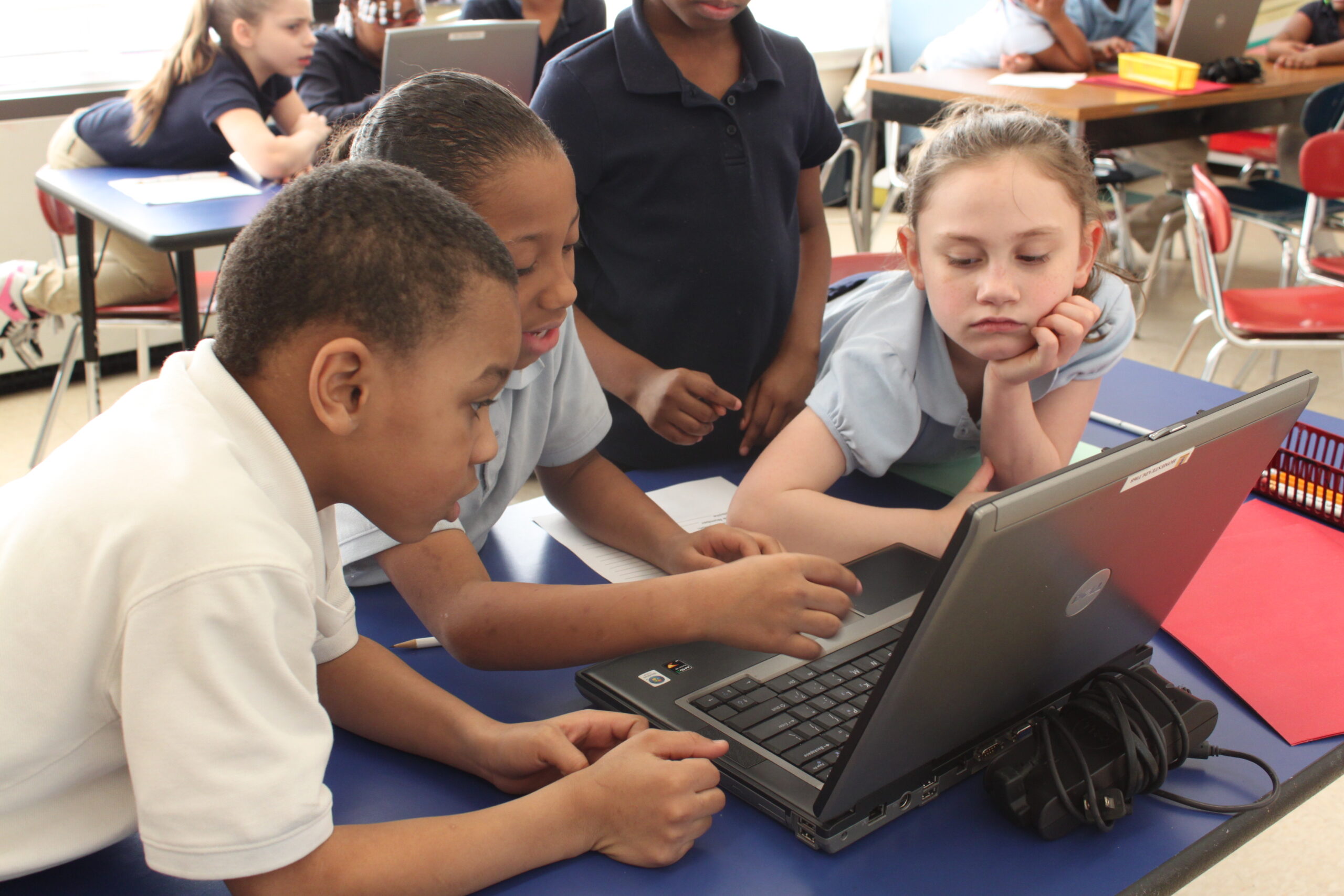 Three youth looking at a laptop computer
