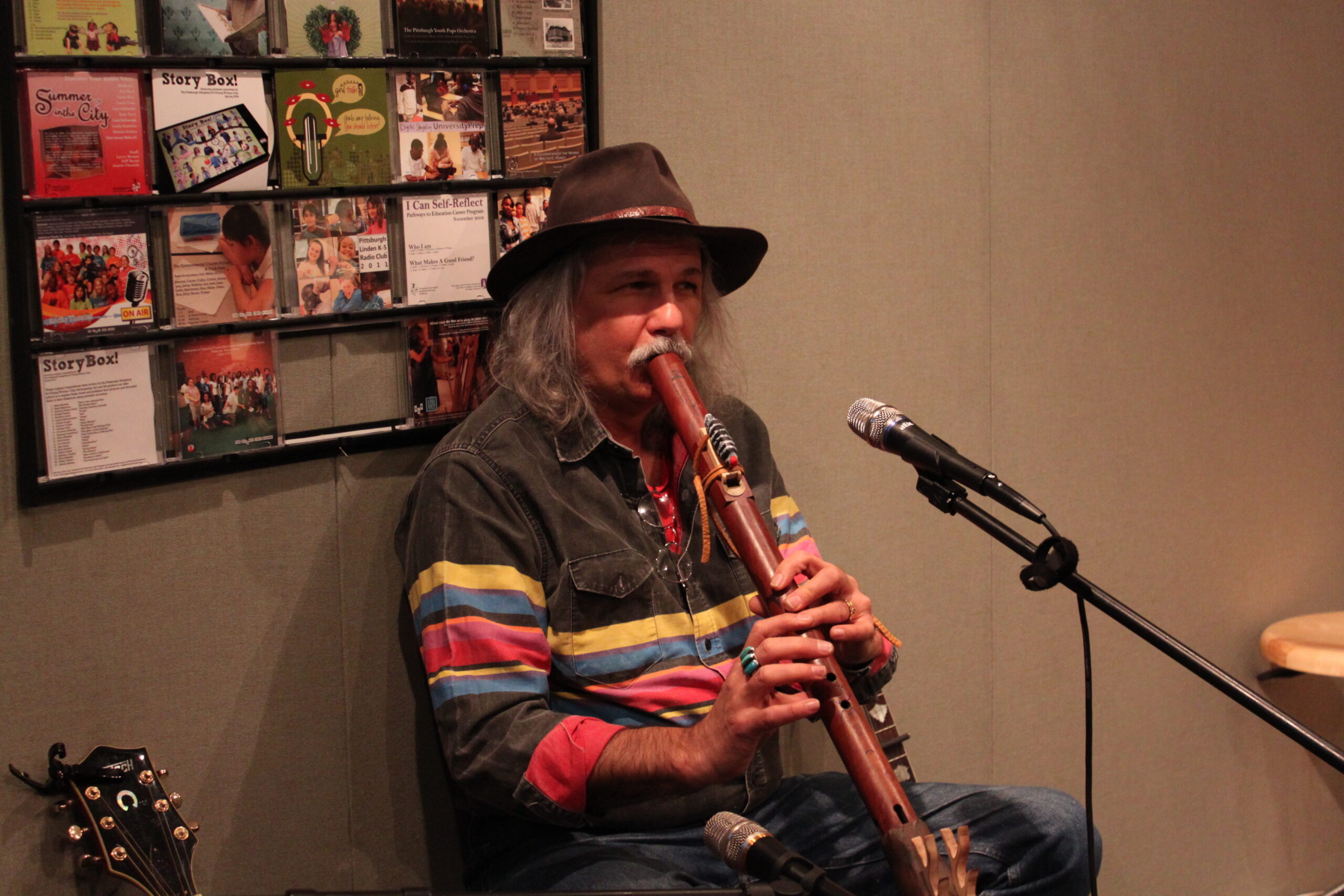 An adult playing an ethnic instrument in a radio studio