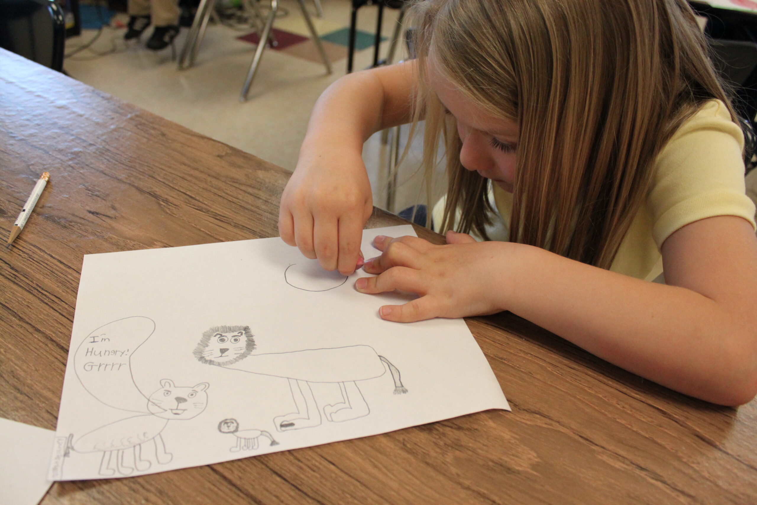 A youth drawing on a piece of paper on a brown table