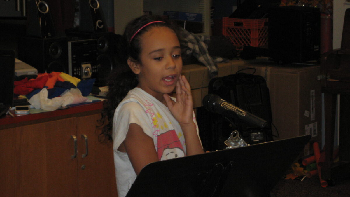 Spring Hill K-5 2013 A youth speaking into a microphone while looking at a music stand