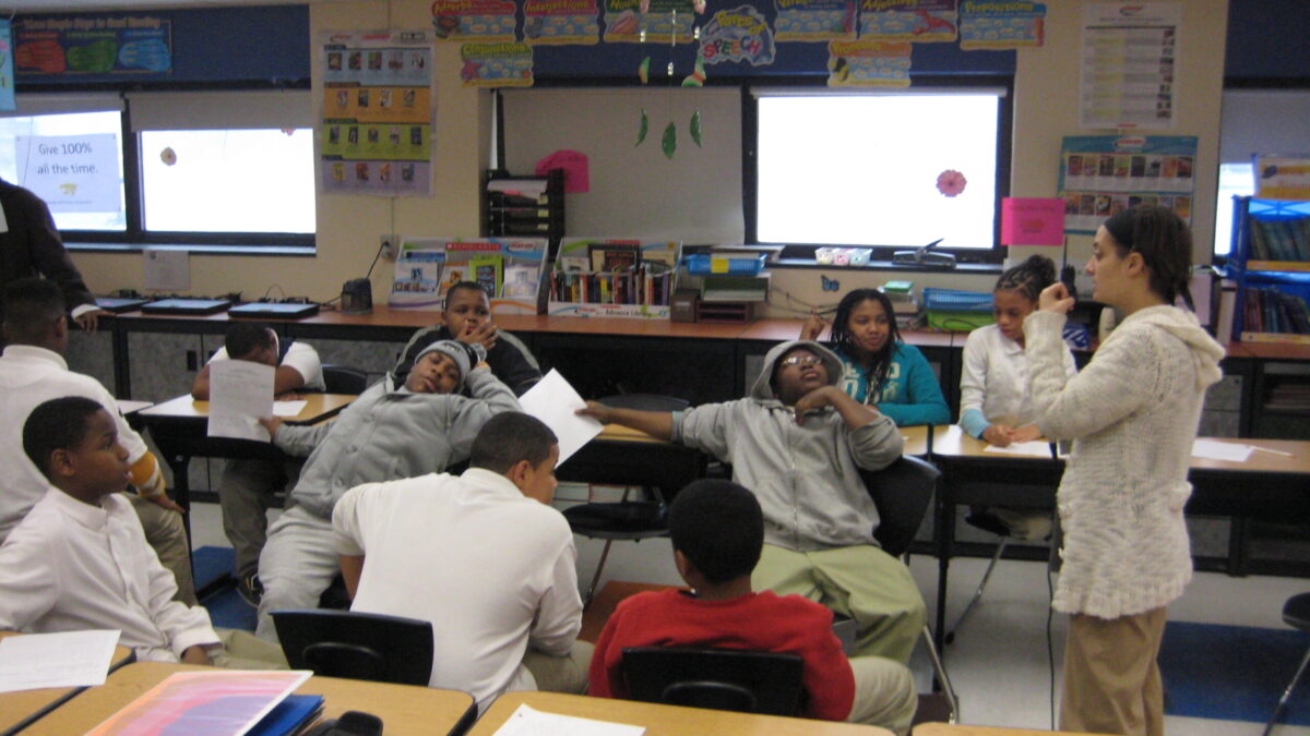Ten youth sitting in a classroom listening to an adult speaking to them