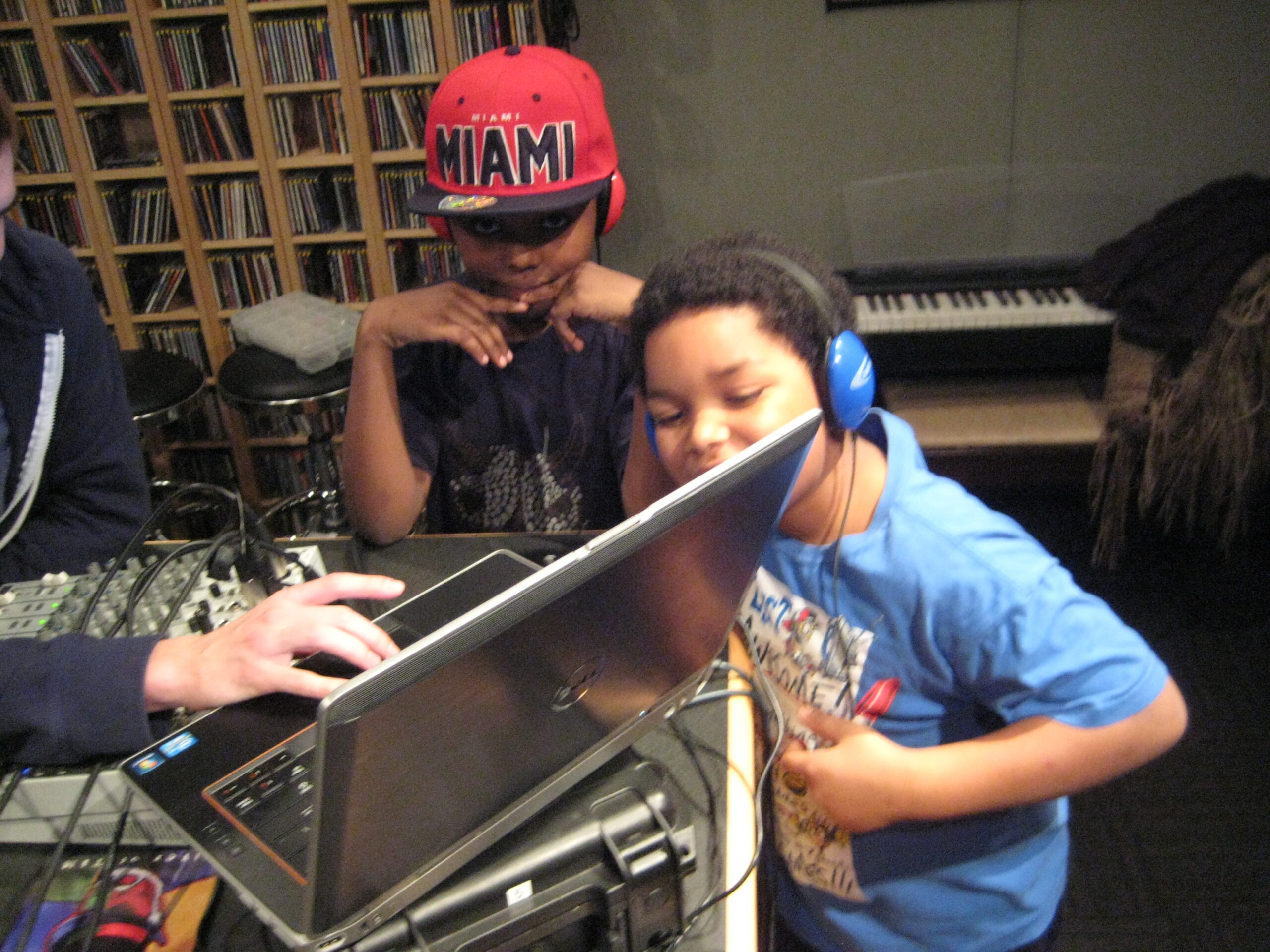 Two youth wearing headphones looking at a laptop computer in a radio studio