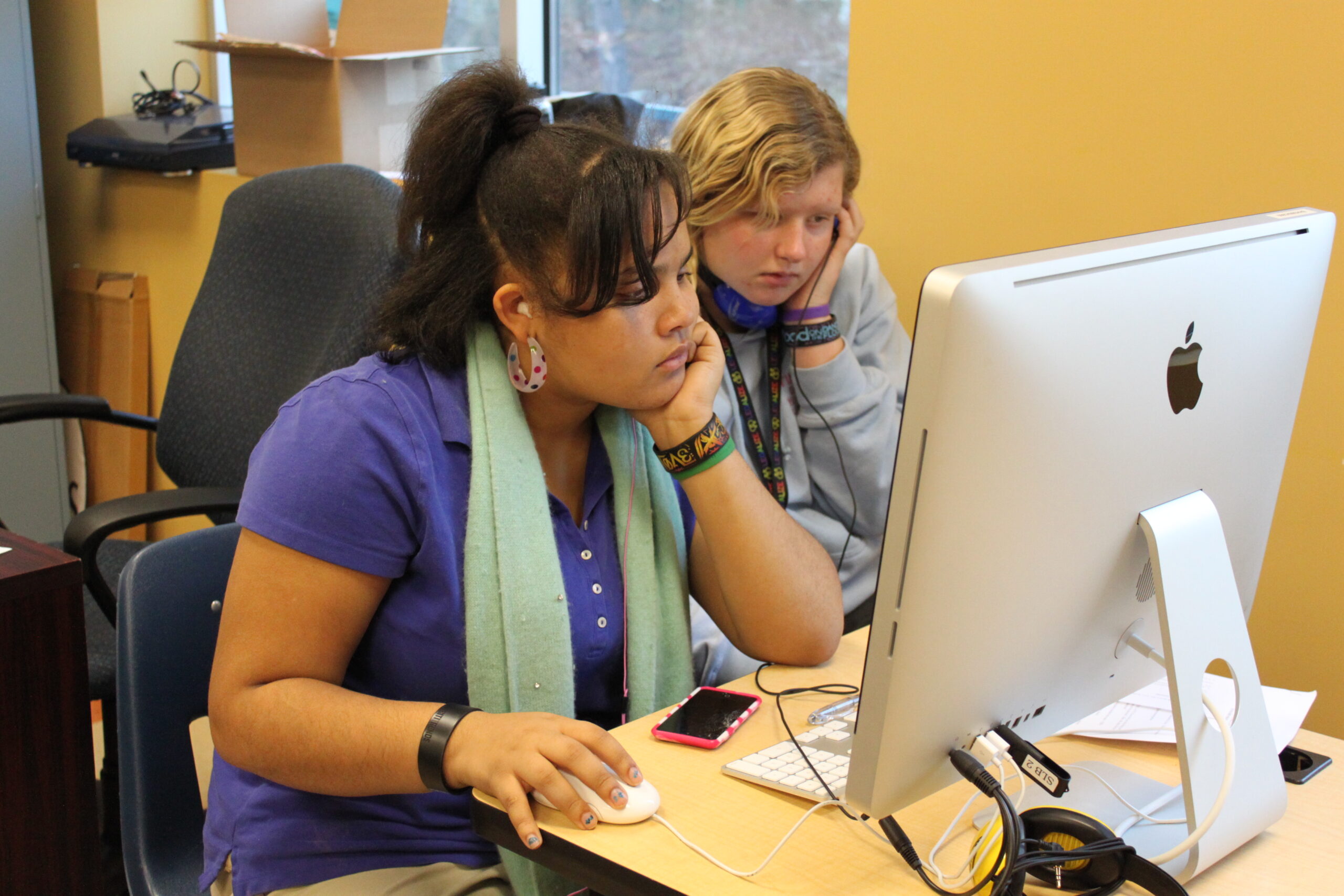 Two teens looking at a computer screen in a classroom