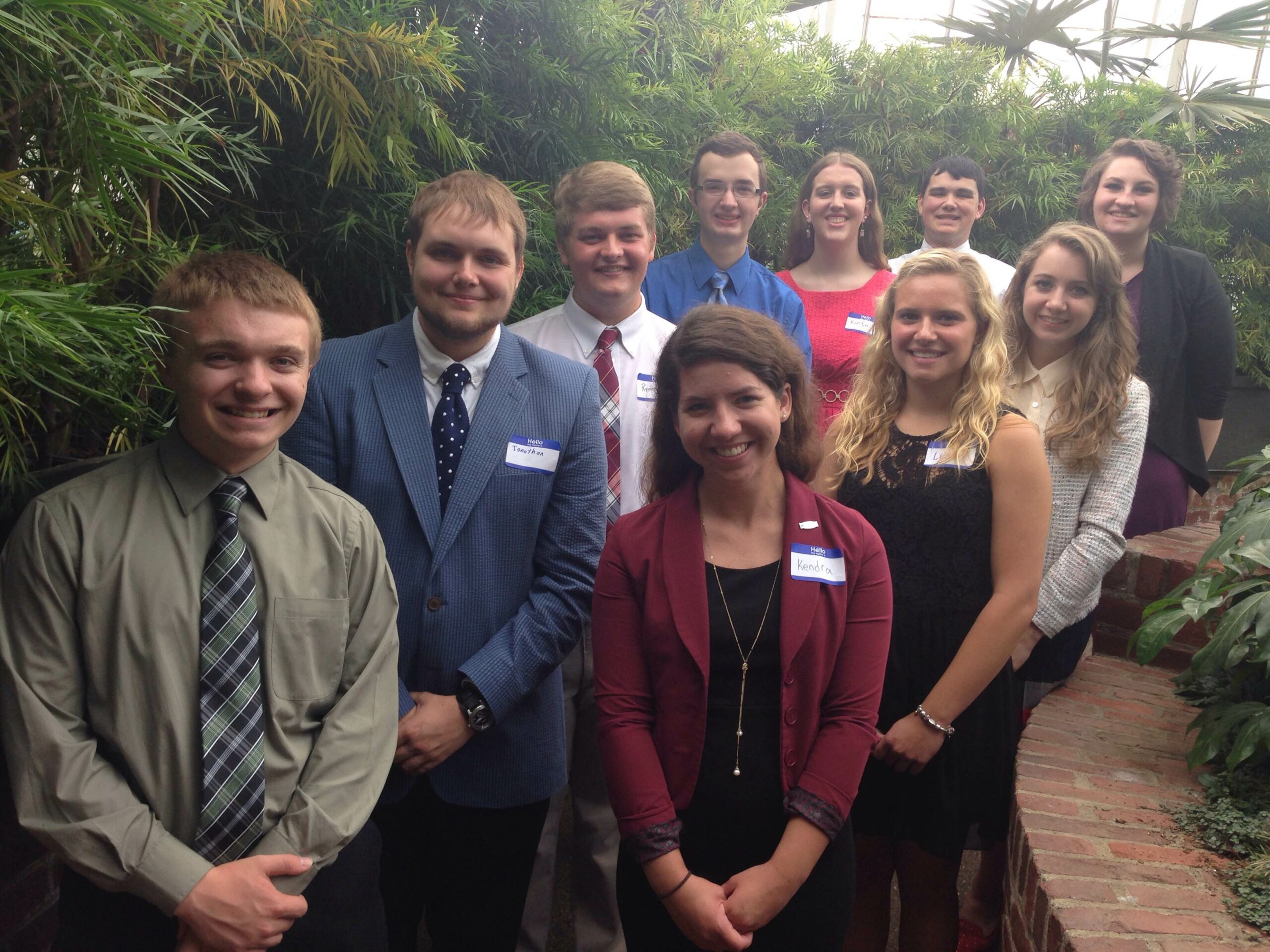 Ten teens smiling and standing in profile in a forest