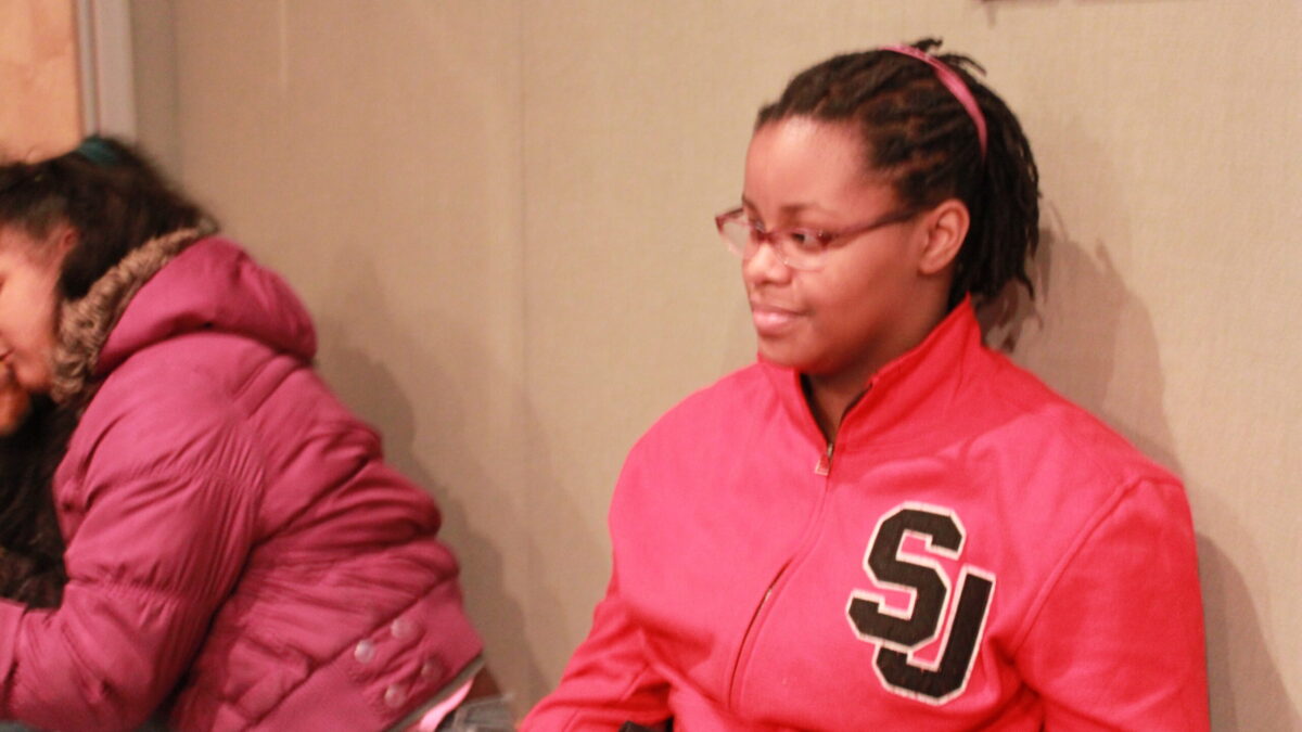 Two individuals sitting while looking to the left in a radio studio