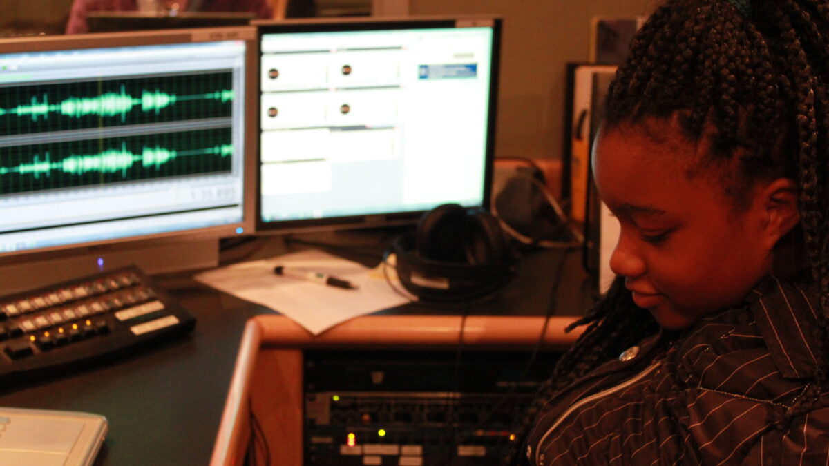 A youth looking at computer screens in a radio studio