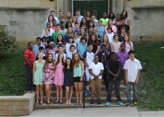 A large group of teens standing in profile on a set of stairs
