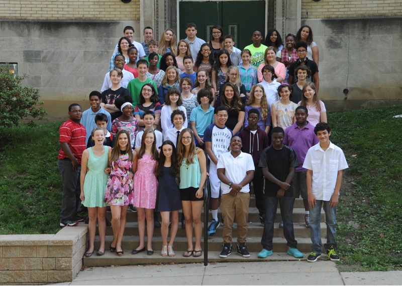 A large group of teens standing in profile on a set of stairs