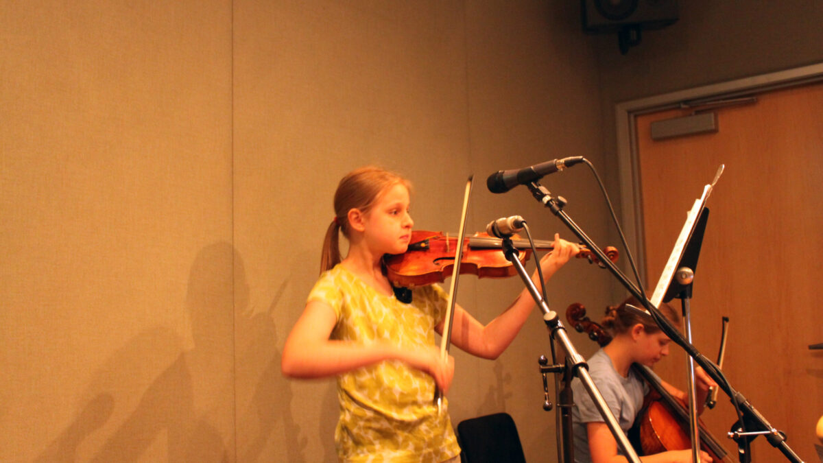 A youth playing a violin and a youth playing a cello in a radio studio