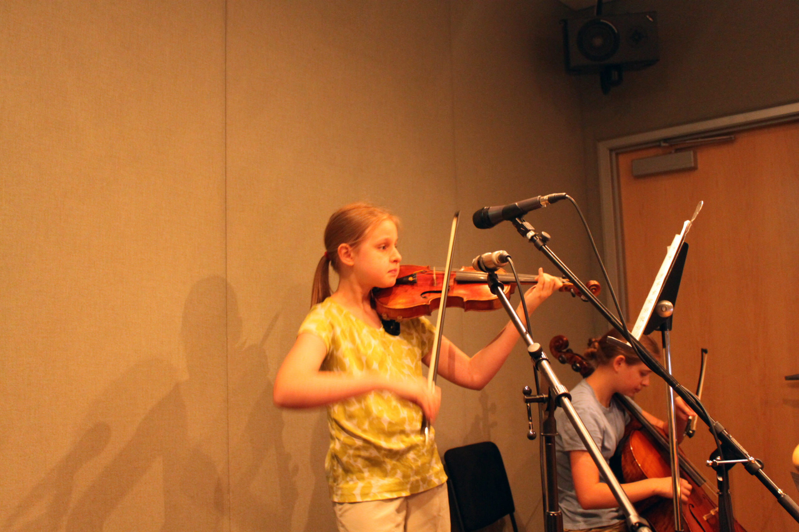 A youth playing a violin and a youth playing a cello in a radio studio