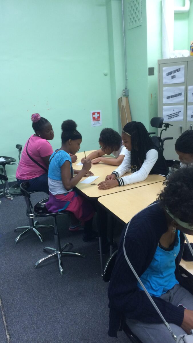 Six youth writing on pieces of paper on classroom desks