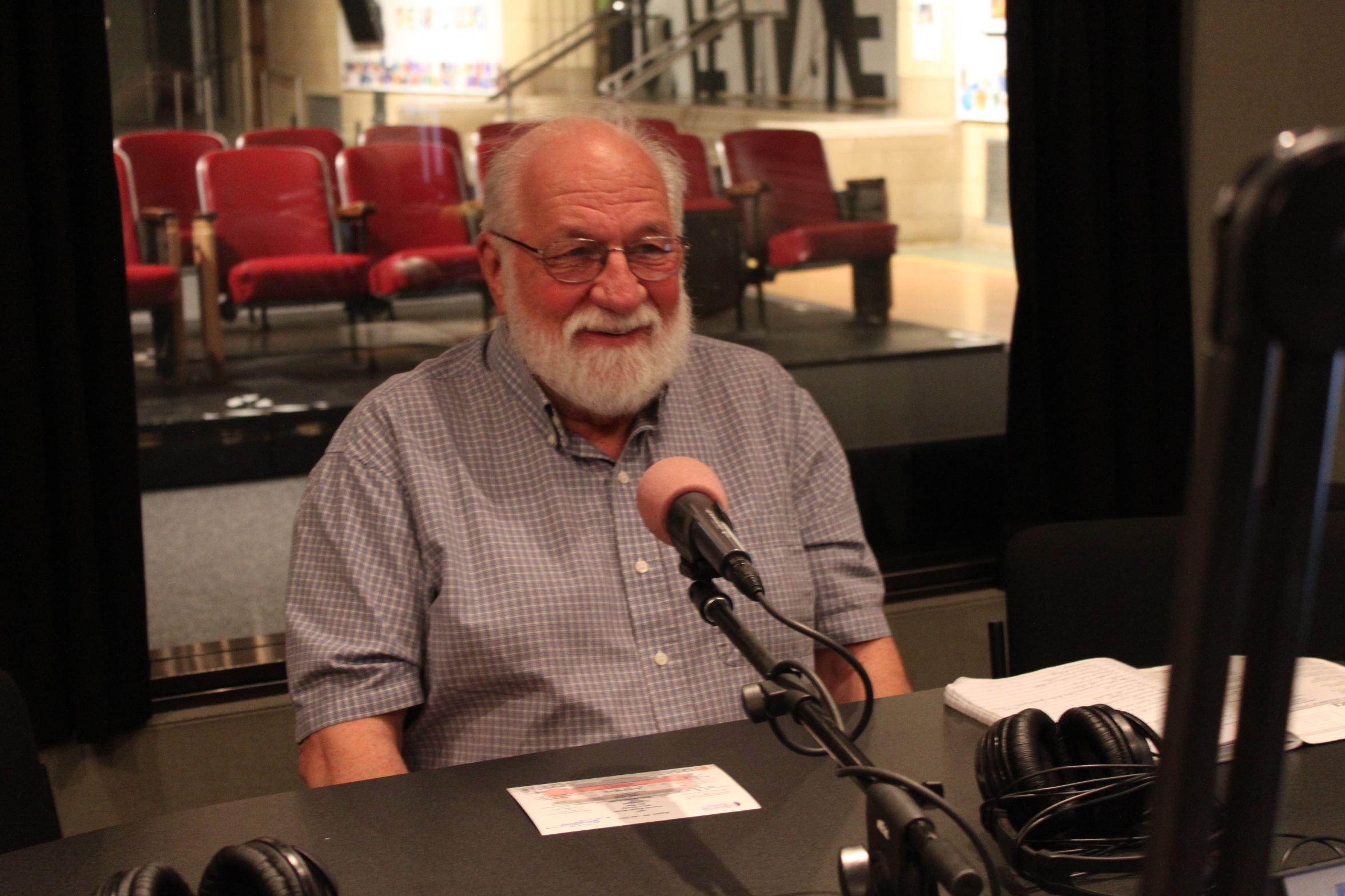 An adult sitting behind a microphone in a radio studio