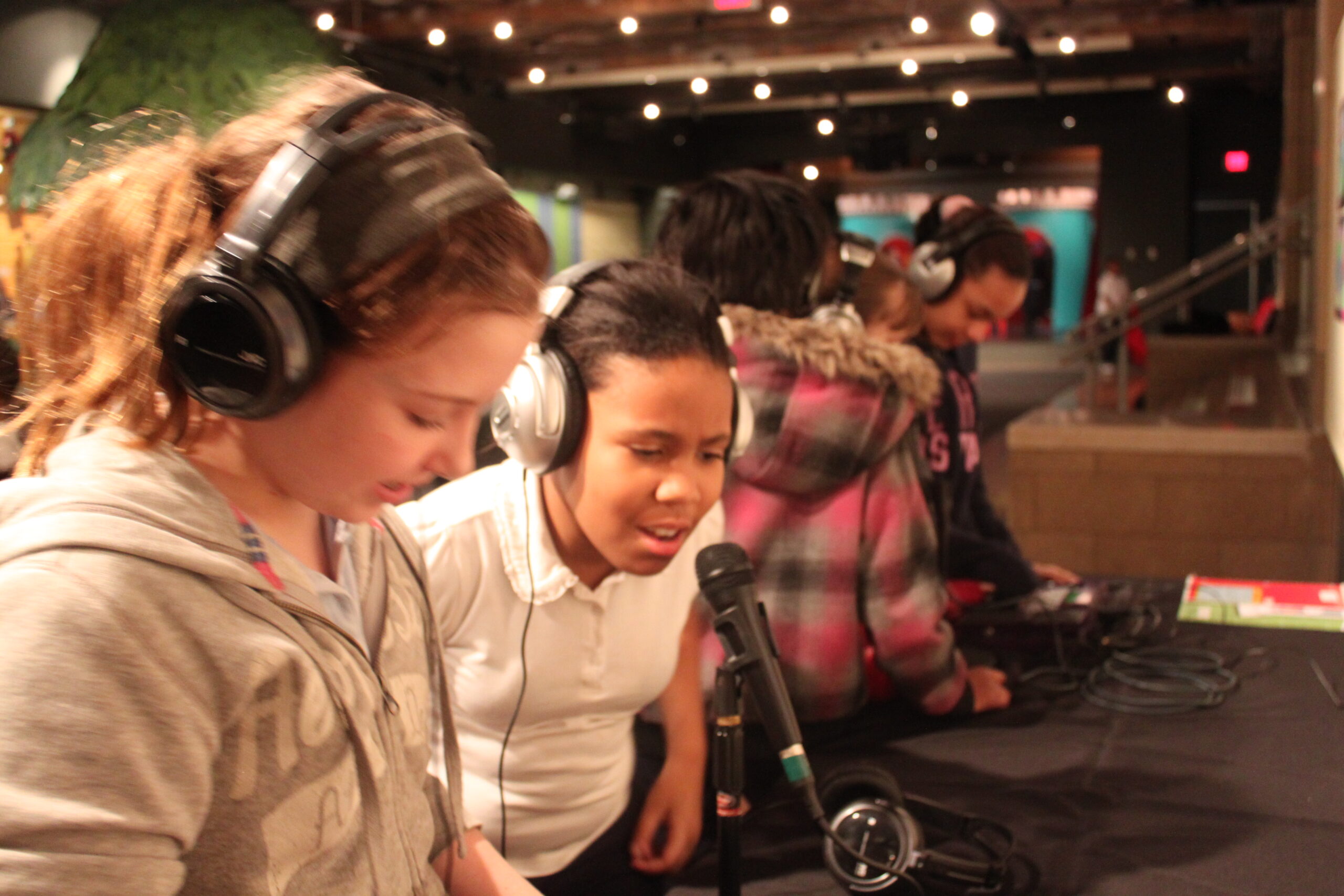 Four youth wearing headphones speaking into microphones